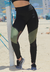 Calça legging cintura alta assimétrica em preto e verde militar, com detalhe em tulê, em ambiente de praia.