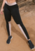 Calça legging fitness preta com faixa chocolate, modelagem ajustada e cintura alta, usada por uma modelo em ambiente natural.