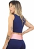 Regata cropped azul com detalhe rosa na cintura, vista lateral de uma mulher com cabelo longo e tatuagens.