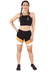 Mulher usando um conjunto fitness cropped preto com shorts de faixas preto, branco e amarelo, posando de frente.