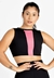 Modelo usando cropped fitness preto com detalhe rosa na frente, em fundo branco.