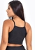 Cropped preto fitness com detalhe transparente, visto de costas.