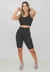 Modelo usando conjunto fitness cropped e bermuda na cor preta, ideal para atividades físicas.