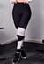 Calça legging cintura alta preta com detalhe de tela branca, usada em ambiente de academia.