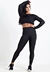 Modelo usando conjunto fitness preto com calça legging e cropped de manga longa em tecido Dry.