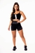 Modelo vestindo conjunto fitness preto com cropped e short cintura alta, destacando detalhes em tela, ideal para academia.