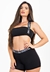 Modelo usando um conjunto fitness preto com cropped e short, destacando a parte superior com alça estampada.