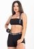 Modelo usando conjunto fitness preto com cropped e short, segurando um haltere.