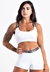 Mulher usando um conjunto fitness branco composto por cropped e short, com detalhes em preto nas alças e na cintura.