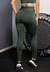 Mulher de costas usando calça legging verde com elástico na cintura alta, em ambiente de academia.