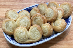 Palmeritas dulces recién horneadas en un plato azul, con un acabado dorado y espolvoreadas con azúcar.