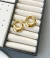 Brinco redondo liso em tom dourado, semijoia banhada a ouro 18k, apresentado em uma caixa de joias com rolos de proteção.