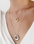 Colar longo em semijoia banhada a ródio branco e colar curto em semijoia banhada a ouro 18k, ambos sobre uma blusa branca.