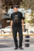 Homem usando uma camiseta oversized preta com estampa de lobo e a frase "BE A WOLF", posando em ambiente urbano.