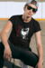 Jovem sentado usando uma camiseta preta com estampa de personagem de fantasia.