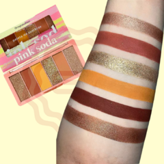 Paleta Pink Soda com seis tons, incluindo glitter e matte, ao lado de amostras no braço.