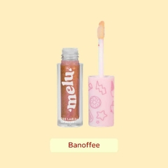 Gloss labial com brilho da marca Melu, na cor Banoffee, apresentado em um frasco transparente ao lado do aplicador com a ponta de espuminha e tampa rosa.