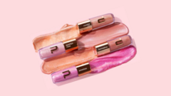 Quatro tubos de gloss labial em tons que variam entre rosa, bege e lilás, com muito brilho. 