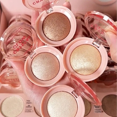Quatro iluminadores Baked Crystal Glow da Ruby Rose em embalagens rosa, exibindo diferentes tonalidades e texturas brilhantes.