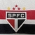 Kit infantil do São Paulo FC, composto por camisa branca com detalhes em vermelho e preto e bermuda branca.