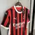 Camisa masculina do Milan I 24/25 na cor preta e vermelha, vista traseira, pendurada em um cabide.Camisa Milan I 24/25 Preto e Vermelho - Puma - Masculino Torcedor