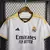 Camisa branca oficial do Real Madrid para torcedores, modelo 23/24 da Adidas, com detalhes em preto e dourado. vini jr