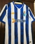 Camisa do time Porto 2024/25 da New Balance, nas cores azul e branco, exibida em um cabide.