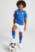 Kit infantil da seleção italiana de futebol, composto por camisa azul e shorts brancos, com detalhes em verde e o logo da Adidas.