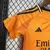 Kit infantil do Real Madrid, uniforme away II 2024/25, na cor laranja, composto por camisa e bermuda.