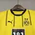 Kit infantil do Borussia Dortmund, composto por camisa amarela e preta e shorts pretos.