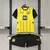 Kit infantil do Borussia Dortmund, composto por camisa amarela e preta e shorts pretos.