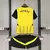 Kit infantil do Borussia Dortmund, composto por camisa amarela e preta e shorts pretos.