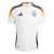 Camisa branca da seleção da Alemanha, modelo home 2024/25, com detalhes em vermelho e preto, e logo da Adidas.