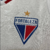 Logotipo do time Fortaleza em uma camisa feminina branca, com detalhes em relevo e uma estrela dourada acima do escudo.