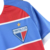 Uniforme do time de futebol Fortaleza, destacando o escudo com as cores azul, vermelho e branco.