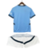 Uniforme infantil do Manchester City, incluindo camisa azul e short branco.