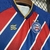 Camiseta infantil do Esporte Clube Bahia, com listras vermelhas e azuis, destacando o logo do clube e detalhes em dourado.