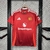 Camisa do Manchester United 24/25 na cor vermelha, com detalhes em branco e logotipo da equipe.