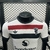 Camisa versão jogador do Manchester United para a temporada 2024/2025, com design em branco, vermelho e preto, destacando o logo da Adidas e do Snapdragon.