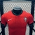 Camisa versão jogador da seleção de Portugal 2024/2025, predominantemente vermelha, com detalhes em verde, logo da Nike e referência a CR7.