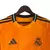 Camisa do Real Madrid 24/25 manto 2 na cor laranja, com detalhes em preto e o logo do clube.