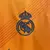 Logotipo do Real Madrid bordado em uma camisa laranja da temporada 24/25.
