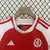 Camiseta infantil do Internacional para a temporada 24/25, mostrando detalhes em vermelho e branco, com logo do clube e etiqueta de tamanho.