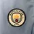 Emblema do Manchester City em um kit infantil, destacando um navio e uma rosa vermelha.