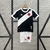 Kit infantil do Vasco com camisa preta e branca e calções brancos, exibindo o escudo do clube.