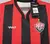 Camisa feminina do Vitória 24/25, com listras vermelhas e pretas, logo da marca Volt e escudo do time.