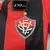 Camisa feminina do Vitória 24/25 com listras vermelhas e pretas, destacando o escudo do clube e uma estrela dourada.