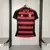 Camisa feminina do Flamengo 25/26, com listras vermelhas e pretas, destacando o emblema do clube e o logo da Adidas, com urubu.