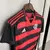 Camisa feminina do Flamengo 25/26, com listras vermelhas e pretas, destacando o emblema do clube e o logo da Adidas, com urubu.