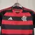 Camisa feminina do Flamengo 25/26, com listras vermelhas e pretas, destacando o emblema do clube e o logo da Adidas, com urubu.